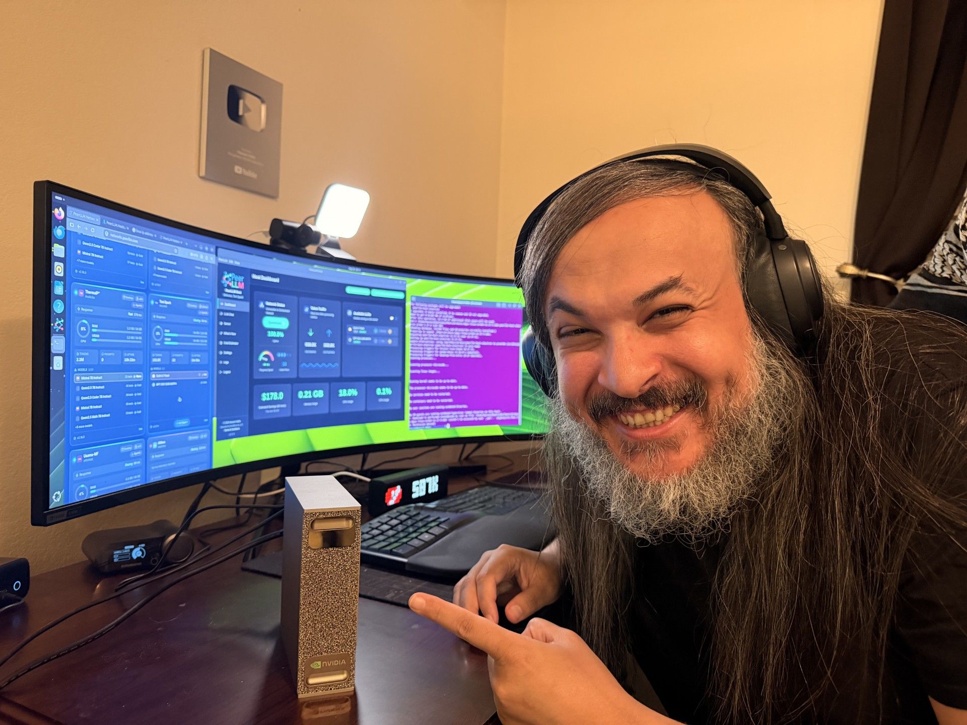 The DGX Spark sitting on my desk beside the keyboard, with the PeerLLM host dashboard and the network site open on the monitor behind it, after the work described in this post
